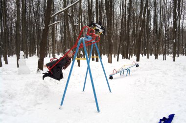 The girl goes for a drive on a children's swing with a heart in park in the winter, Moscow, Russia clipart