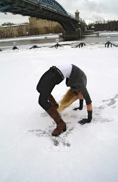 La ragazza costa in una posa il ponte nell'inverno su neve — Foto Stock