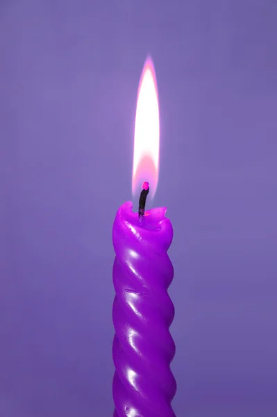 紫色の背景に薄紫色のろうそくを燃やす — ストック写真