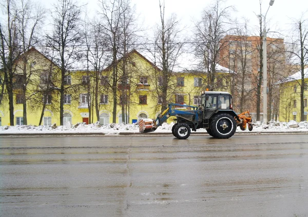 Il trattore che toglie la neve va sulla strada per uno sfondo del hou giallo — Foto Stock