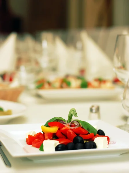 Řecký salát s rajčaty, sýrem a olivami na stůl — Stock fotografie