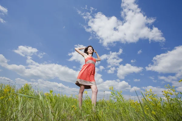 Красива молода жінка стоїть на полі насолоджуючись вітром — стокове фото