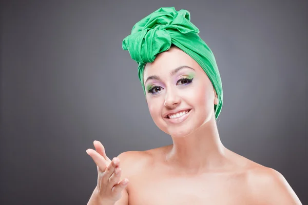Glücklich lächelnde Frau mit grünem Schal auf dem Kopf, die mit der Hand zeigt — Stockfoto