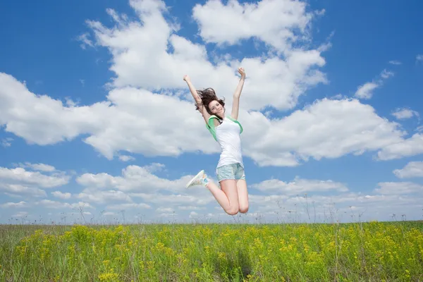 Jumping happy young brunette women on summer field — Stock Photo, Image
