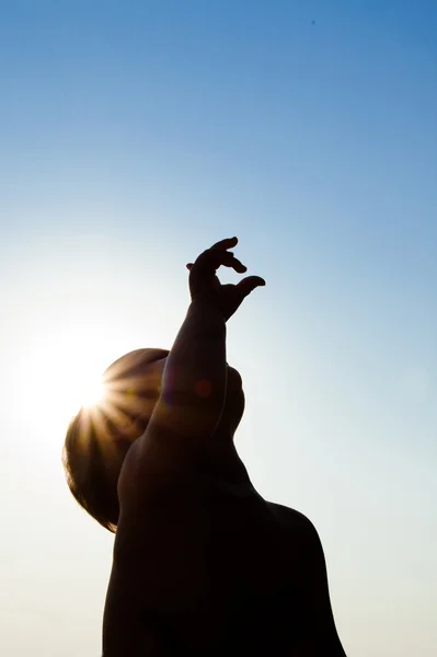 stock image Adorable child silhouette over sunshine pointing up