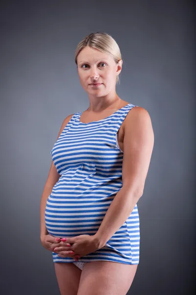 Zwangere gelukkig lachend blonde vrouw in gestreepte mariene shirt te houden — Stockfoto