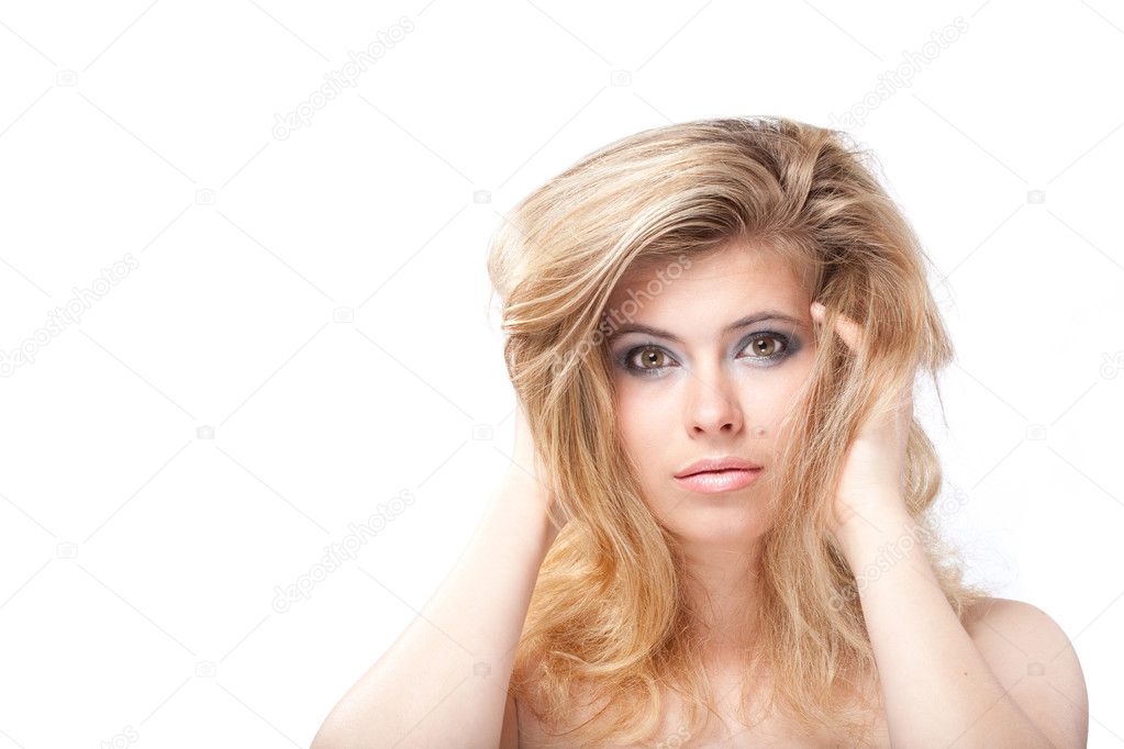 Tempting blonde young woman with large grey eyes holding hair wi