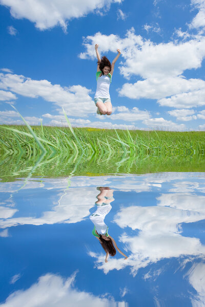 Jumping happy women on field with reflection in the water