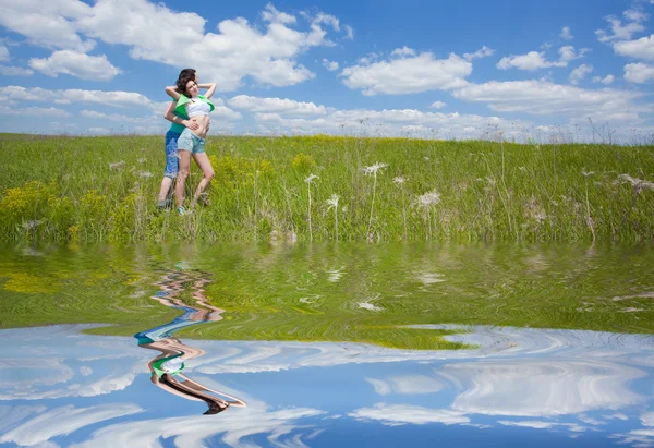 Pareja cariñosa en el campo abrazándose con el reflejo en el agua —  Fotos de Stock