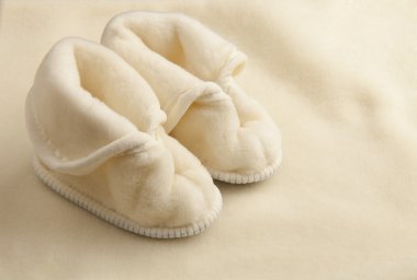 Pair of warm children slippers on a woolen texture