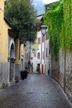 View of a narrow street in Arco, North Italy, with Alps in the background clipart