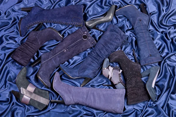 Botas e sapatos azuis femininos colocados em cetim drapeado azul — Fotografia de Stock