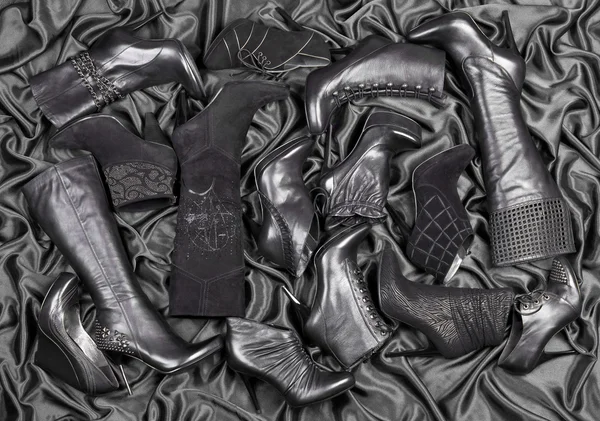 Vrouwelijke zwarte schoenen en laarzen geplaatst op zwart satijnen — Stockfoto