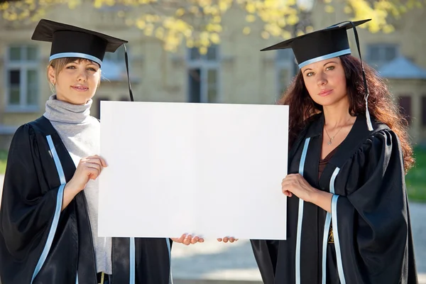 Two graduates hold a clean sheet — Stock Photo, Image