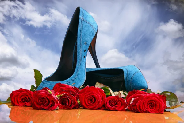 Composition avec des roses rouges et des chaussures féminines bleues sur fond ciel — Photo