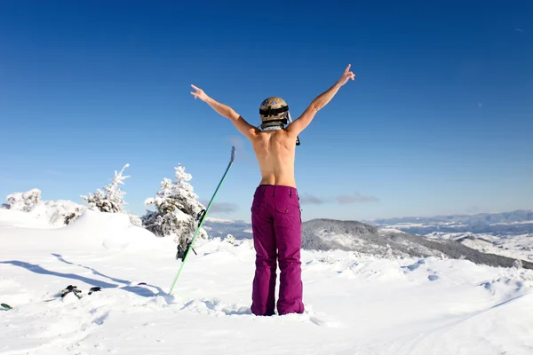 Female skier topless with a ski standing on the heel a back — Stock Photo, Image