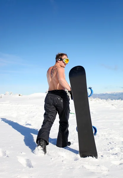 トップレスのスノーボーダー山の上を歩く — ストック写真