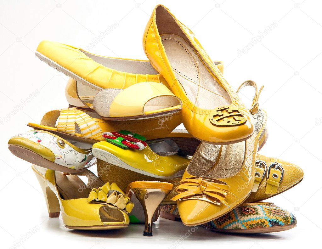 Pile of female yellow shoes isolated on white background