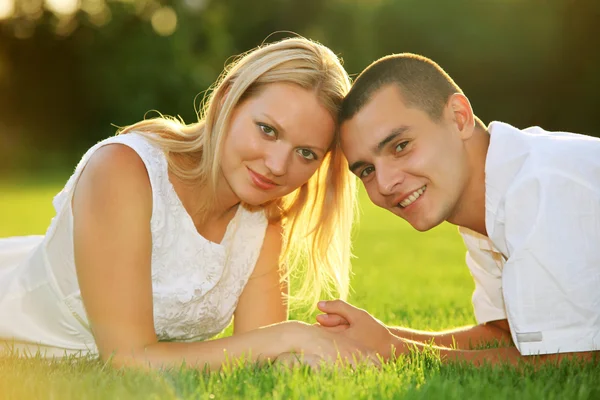 Young happy couple lying down on grass — Stock Photo, Image