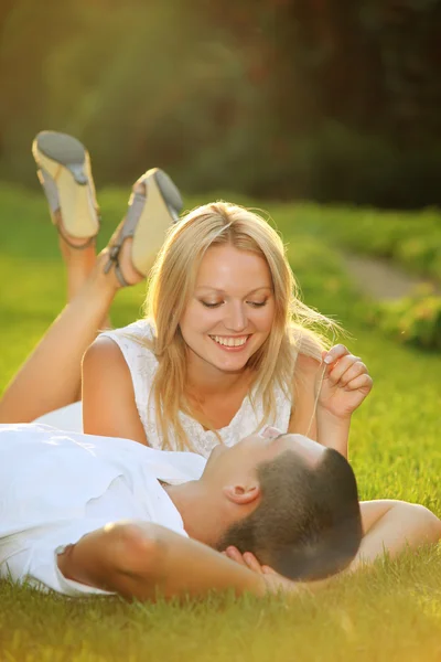 年轻快乐的夫妻躺在阳光下草地上 — 图库照片