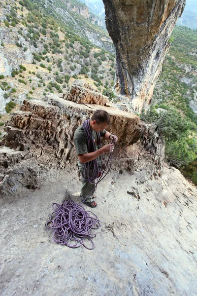 Escalador de roca enrollando una cuerda después del ascenso, vista superior en el escalador con un pintoresco fondo de montaña. Cañón Rodellar, España — Foto de Stock