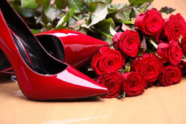 Μεγέθυνση της ζευγάρι κόκκινα παπούτσια γυναικεία και κόκκινα τριαντάφυλλα — Φωτογραφία Αρχείου