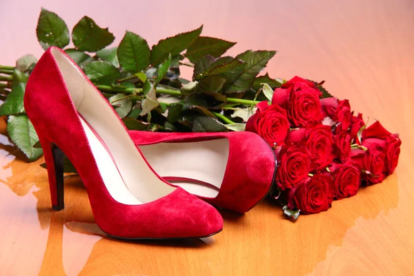 Paar rode vrouwelijke schoenen en bos van rode rozen — Stockfoto