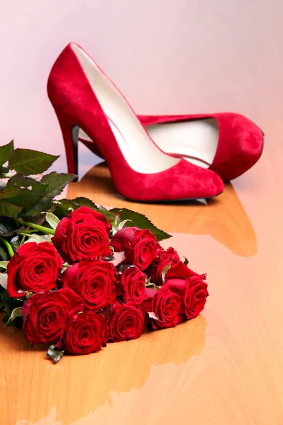 Csokor vörös rózsa és egy pár piros női cipő — Stock Fotó