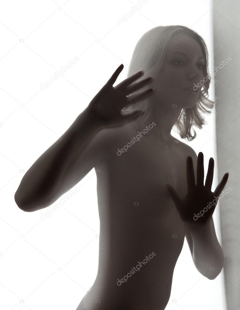 Silhouette of young sexy woman behind textile