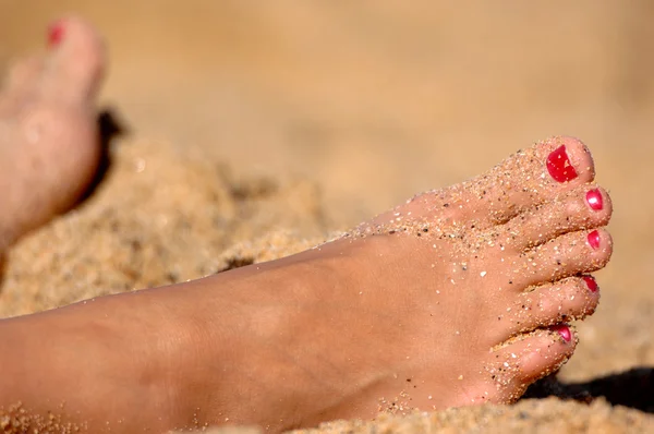 Pies de mujer descansando en la arena — Foto de Stock