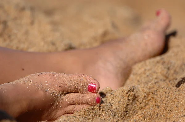 Pies de mujer descansando en la arena — Foto de Stock