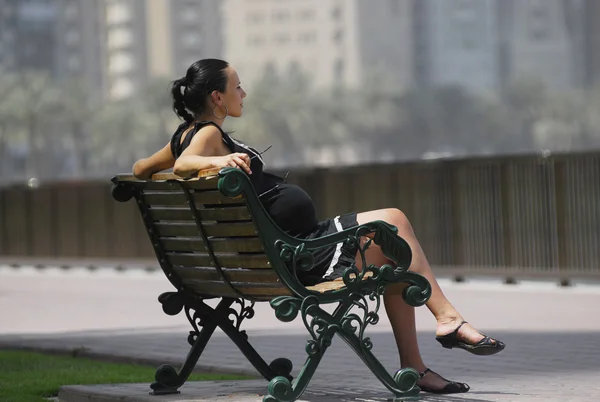 Yang gravid kvinna avkopplande i bänken — Stockfoto