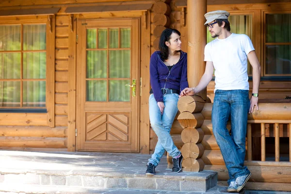 Jovem casal na frente de uma casa de madeira — Fotografia de Stock