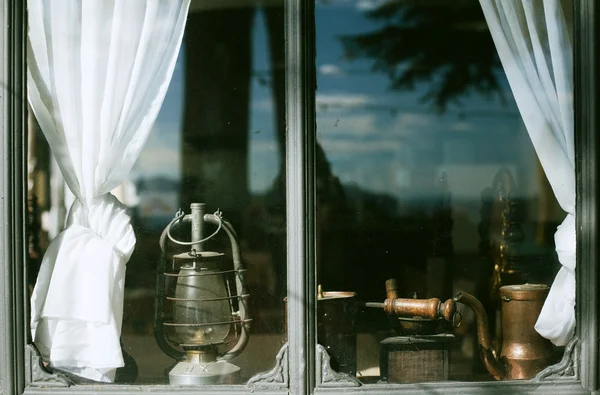 Antique oil lamp, coffee mill and kettle at window-sill — Stock Photo, Image