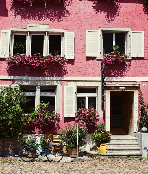 Рожева стіна будинку повна квітів і синього велосипеда — стокове фото