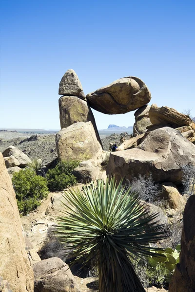 Turystyczne siedzi pod zrównoważony rock — Zdjęcie stockowe