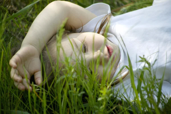 Pěkná malá holčička si klade na zelené trávě — Stock fotografie