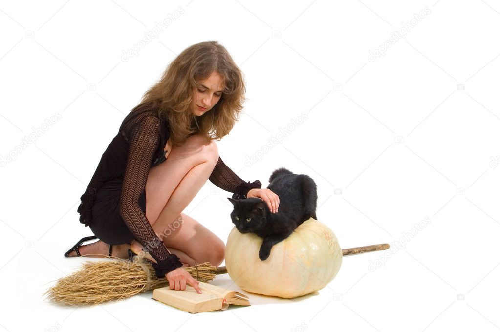 Young attractive witch with pumpkin, broom and black cat
