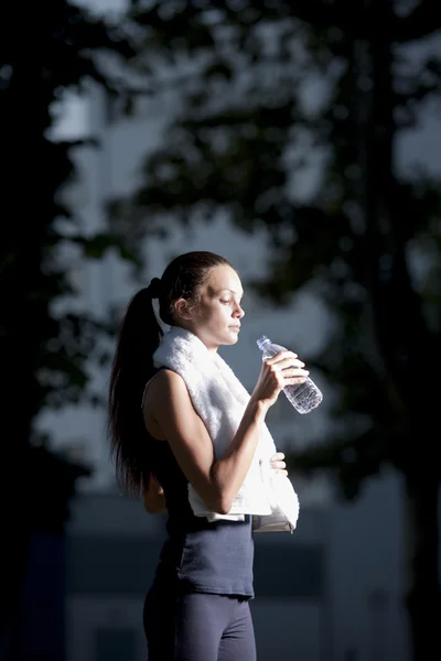 Athletic woman drinking water after jogging — Stock Photo, Image