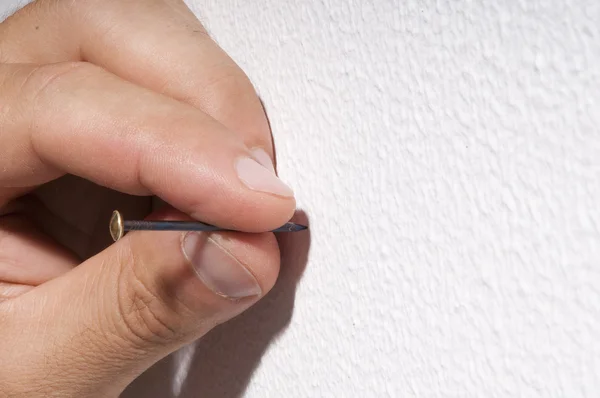 Mannenhand nagel rijden op de muur — Stockfoto