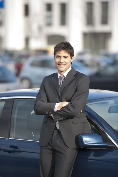 Jovem empresário apoiando-se em seu carro — Fotografia de Stock