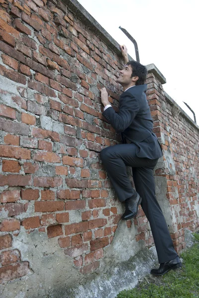 Uomo d'affari arrampicata su un muro di mattoni — Foto Stock