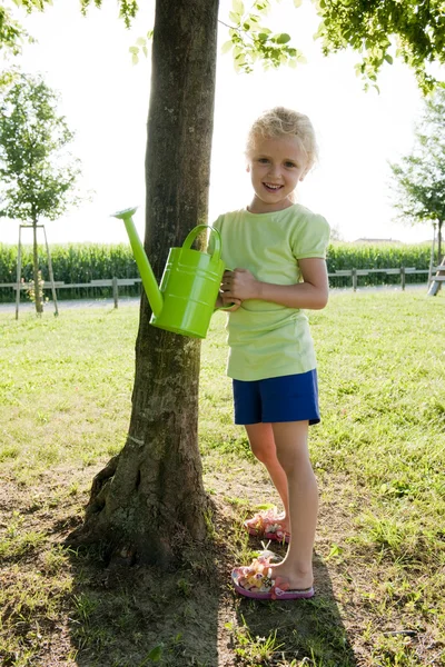 Malá dívka zalévání strom — Stock fotografie