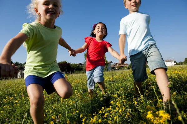 Tres niños corriendo tomados de la mano —  Fotos de Stock