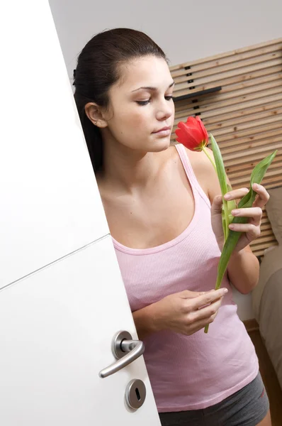 Adolescente oliendo un tulipán en su dormitorio — Foto de Stock