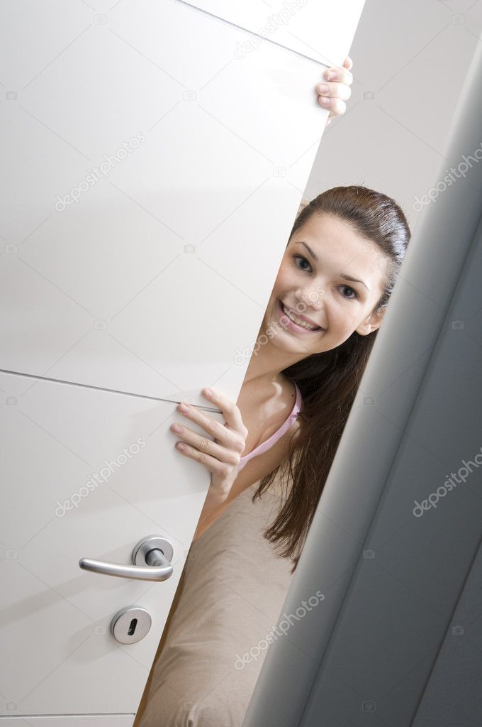 Teenage girl peeking through door