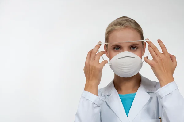 Fiatal női orvos védő maszkot visel — Stock Fotó