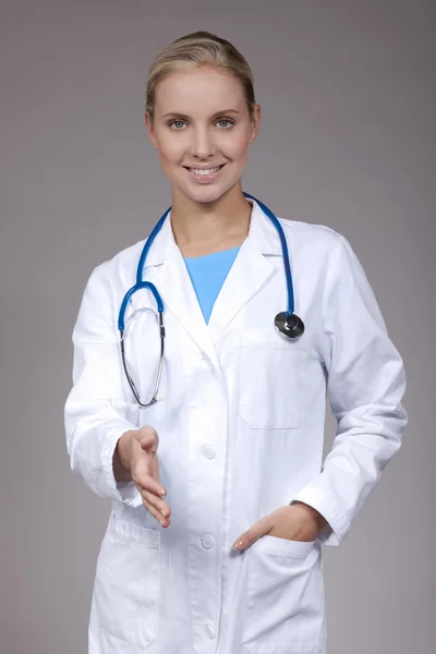 Щаслива жінка-лікар дає руку для рукостискання, ізольована на білому — стокове фото