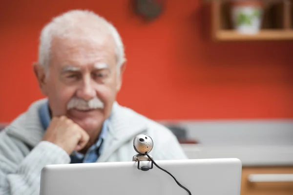 Starszy mężczyzna, który mówi przez kamerę internetową — Zdjęcie stockowe