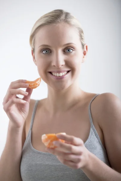 Красивая женщина ест апельсин — стоковое фото